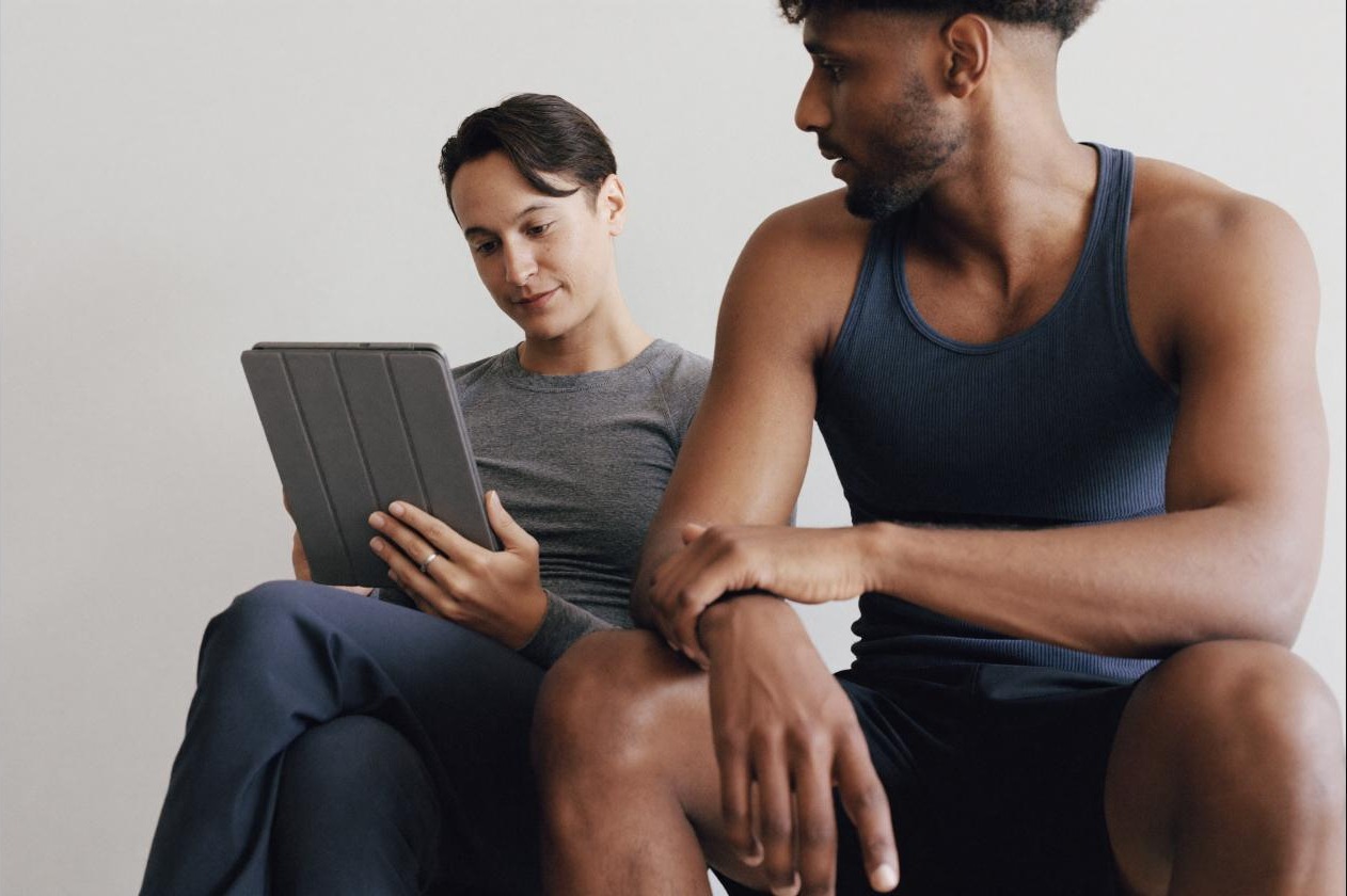 Coach and athlete reviewing a training plan on a tablet, mapping out a lighter deload week