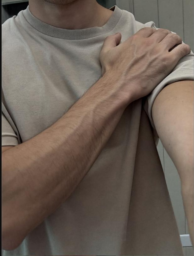 Person performing a cross-chest shoulder mobility stretch