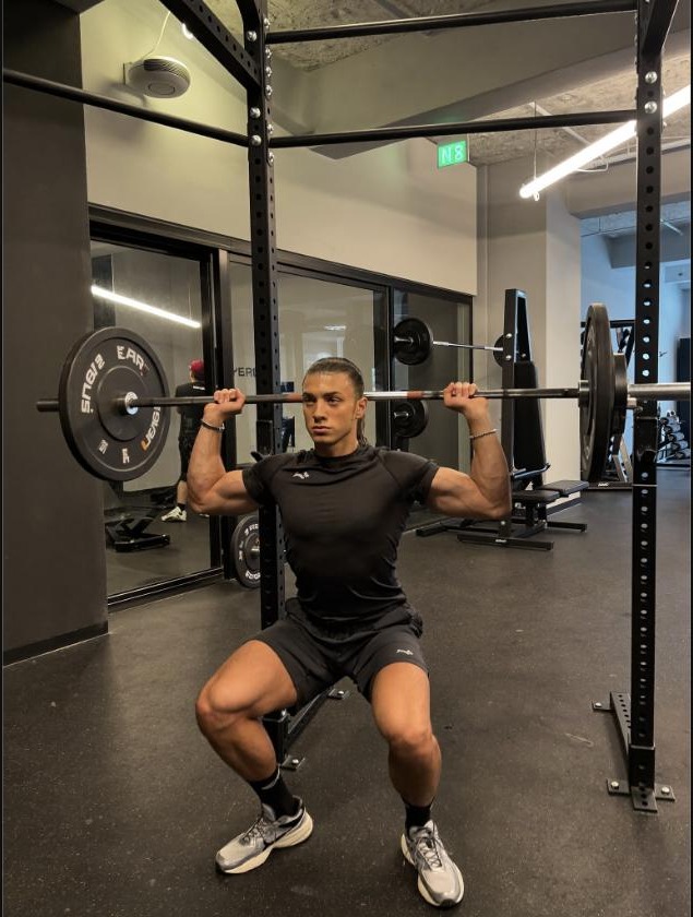 Man performing a barbell back squat, representing progressive overload training