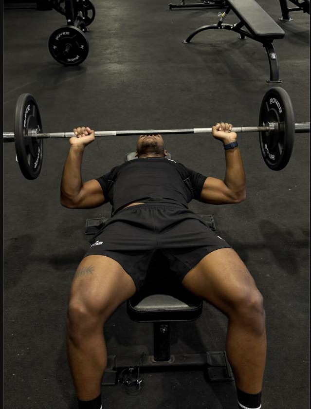 Man performing a barbell bench press during a strength training session