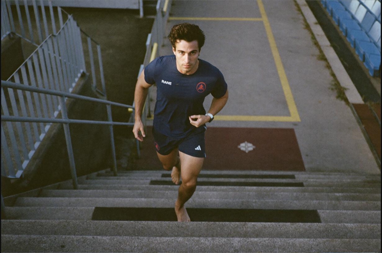 Man running up stadium stairs outdoors, a repeated step-by-step effort that builds momentum over time