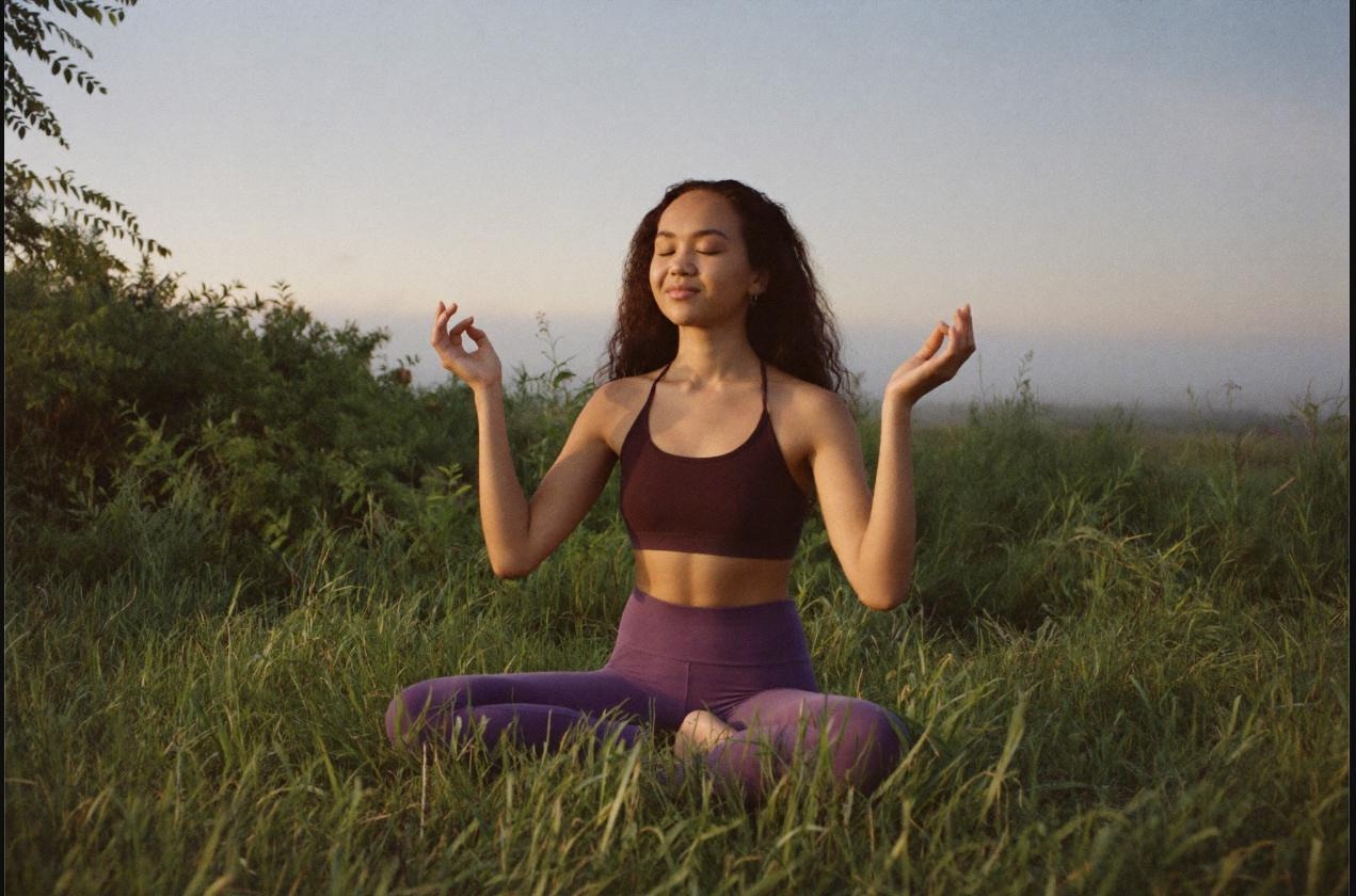 Woman sitting quietly in meditation outdoors at sunrise, a still moment used to check a daily readiness reading