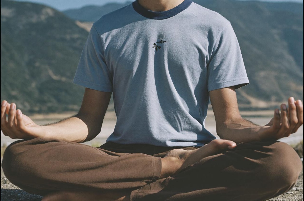 Man in a calm seated meditation pose at sunrise, representing rest and recovery