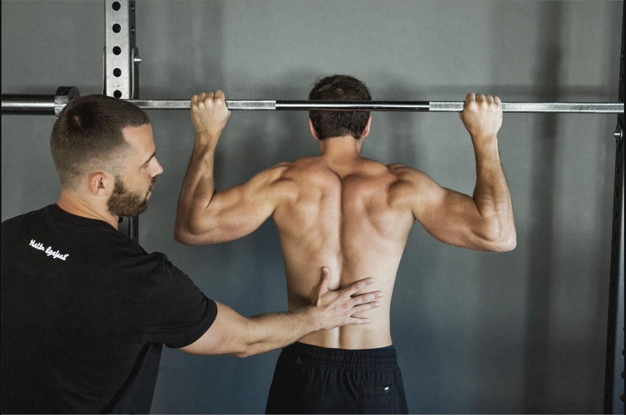 Coach correcting a client's squat form, representing training with intent rather than pushing to failure