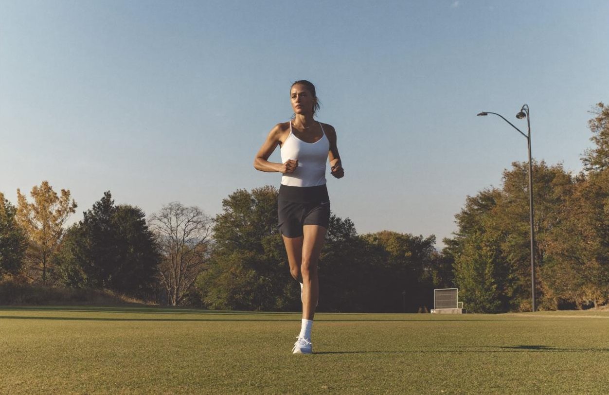 Runner jogging across a sports field in morning light